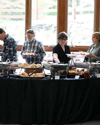 Members sharing a meal in the fellowship hall, windows onto the grounds