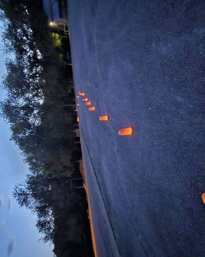 Paper luminaria lining the drive at dusk, leading toward the building