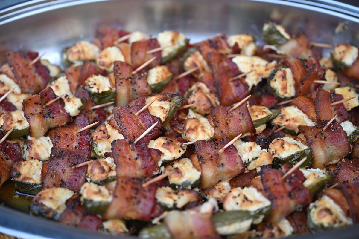 A chafing pan of bacon-wrapped appetizers on skewers