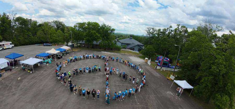 An aerial photograph of the congregation standing together in the shape of a peace sign on the grounds